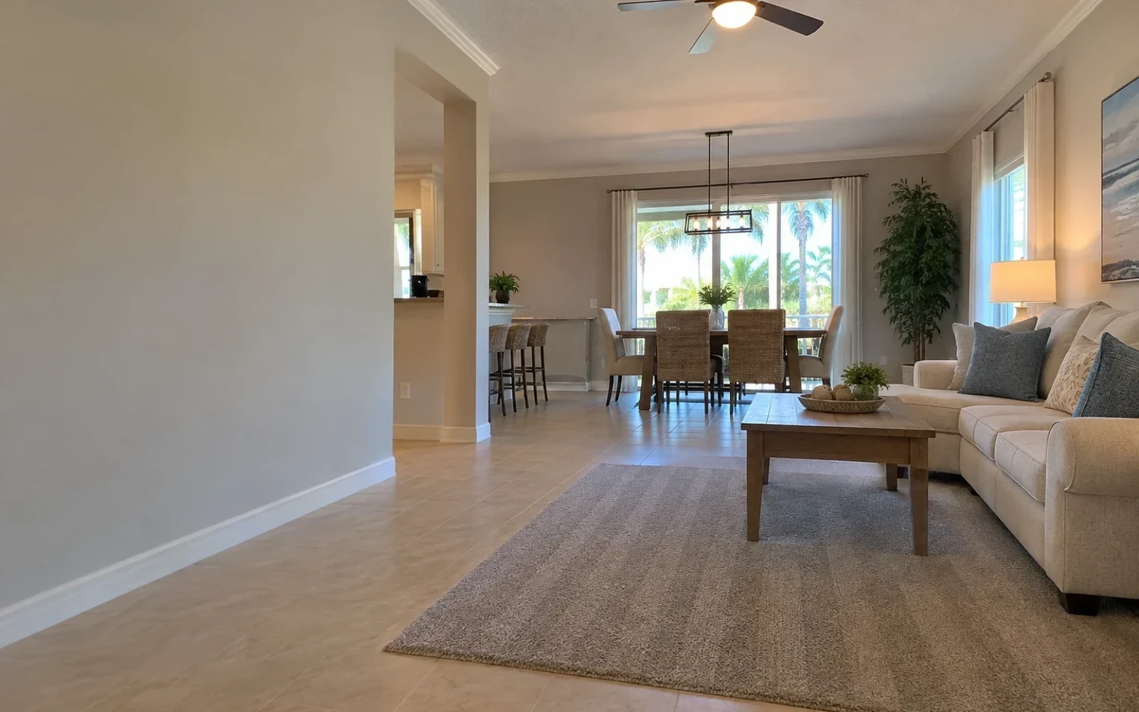 An open living and dining area with clear floors, wiped surfaces, vacuum lines on a rug, and daylight from a large window.